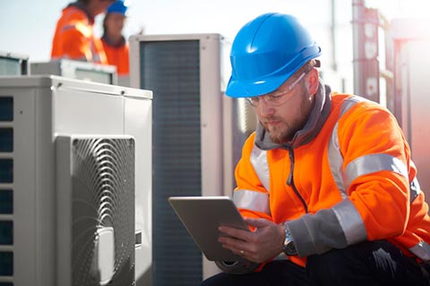worker using tablet device on site with HVAC unit