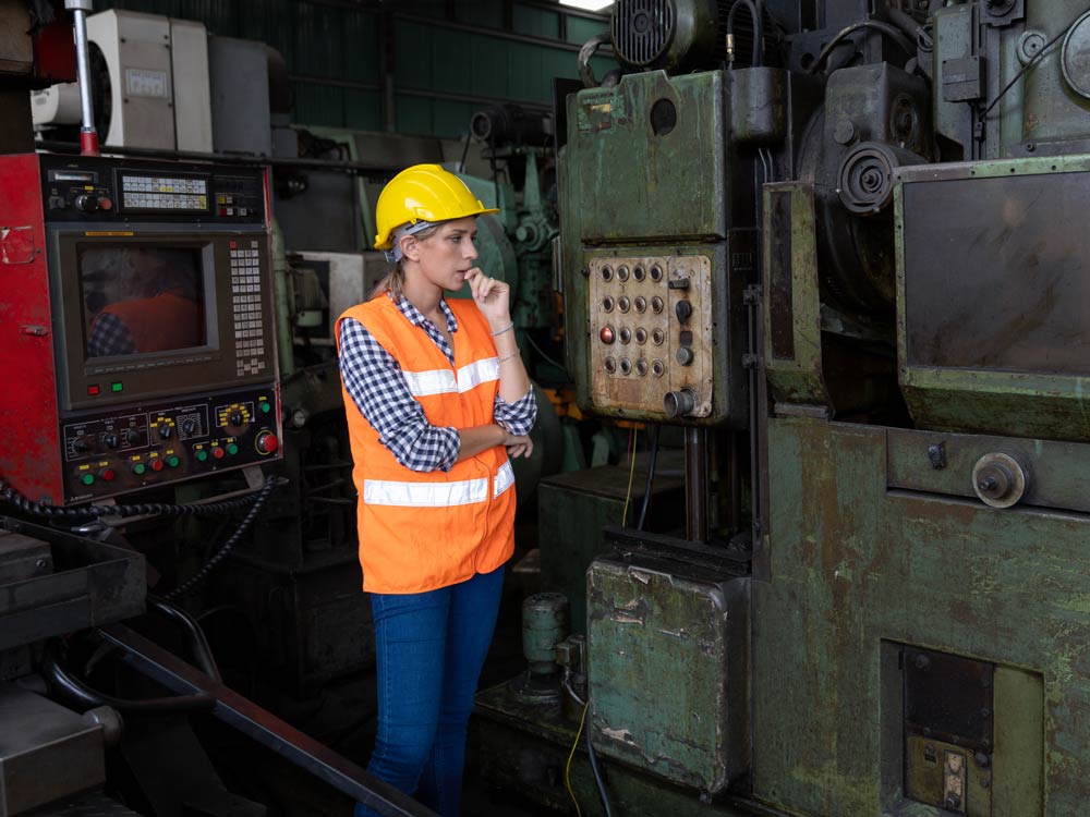 Worker looking at machinery and thinking