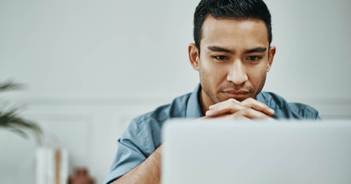 A person is sat down looking intently at a laptop screen