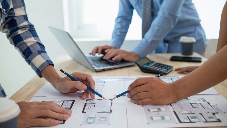 Three office workers reviewing house plan