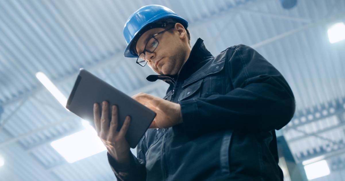 Contractor managing business on an ipad wearing hard hat