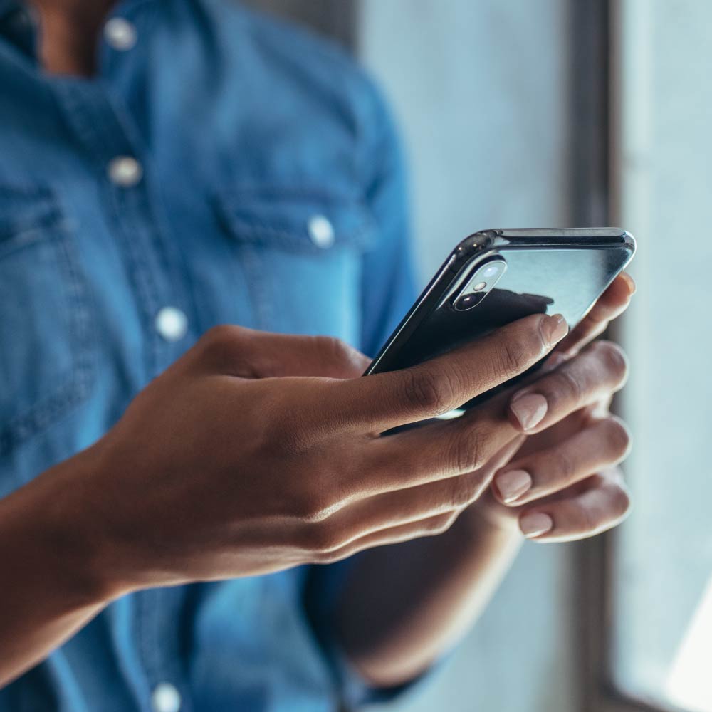 A black mobile device is being held by a person in a blue shirt