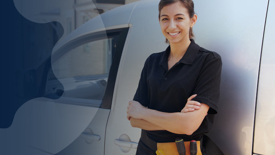 A field technician stands beside her van