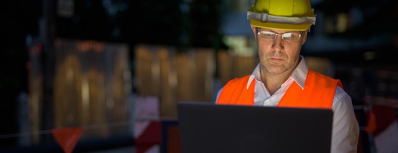 Person wearing protective equipment at a job site using a computer