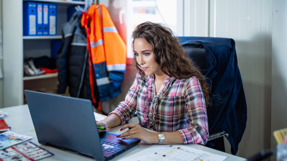 A woman sitting in an office, generating reports on a computer.