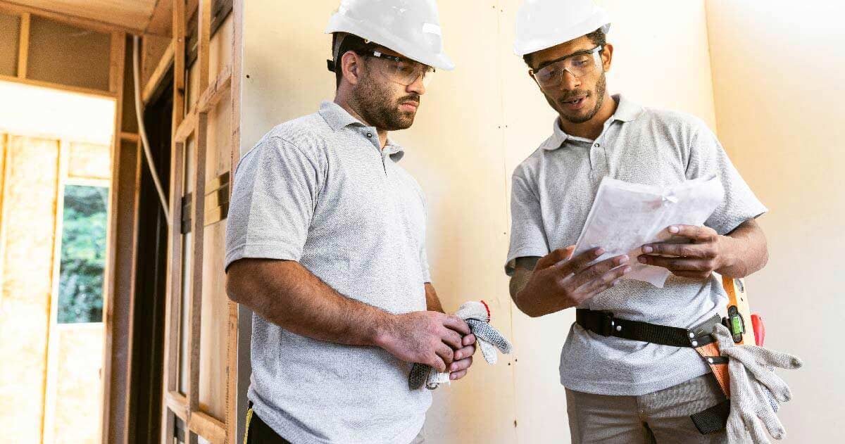 Two men in hardhats looking at project plan
