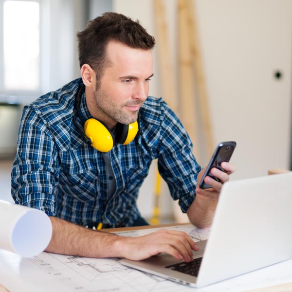 Man operating both a smartphone and a laptop