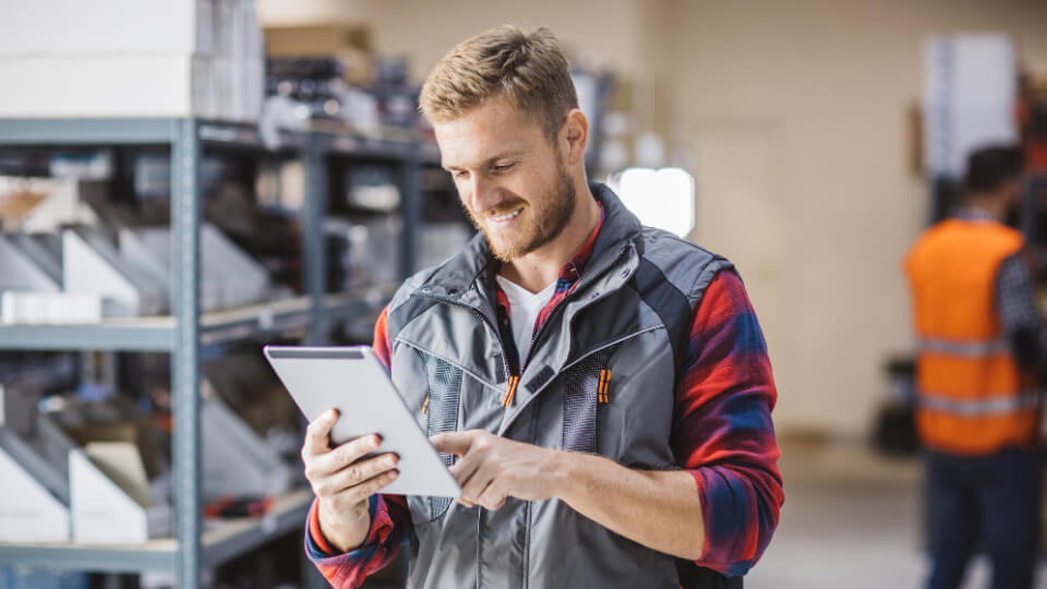 A man in a warehouse looking at a tablet