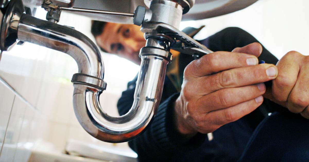 Plumber working on a pipe with a wrench