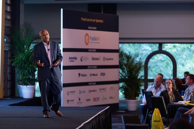 A speaker on-stage presenting at Simprosium Sydney 2025