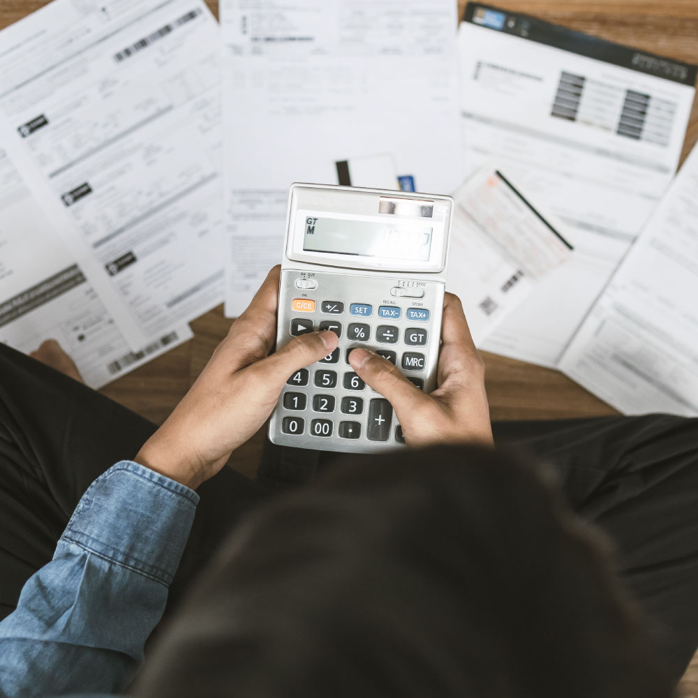 Person holding a calculator with papers spread out on the floor