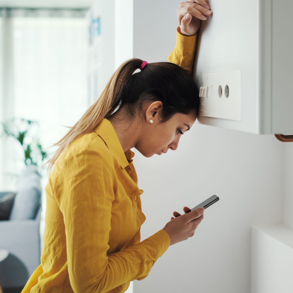 Woman leaning head against cabinet door while looking at her phone