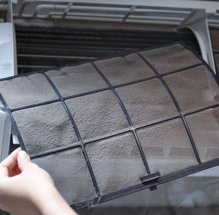 A piece from an HVAC unit covered in dust and debris