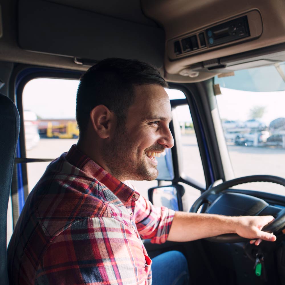 A person in a truck driving and smiling