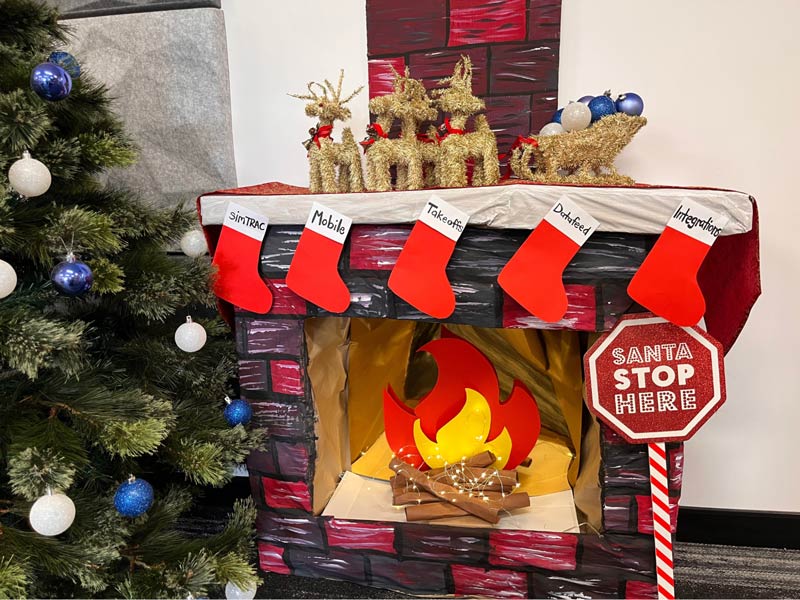 A homemade red fireplace and christmas tree with Simpro Add-Ons labeled stockings attached