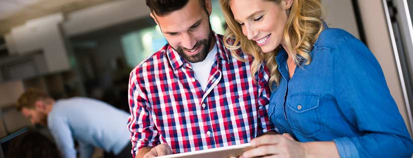 2 people looking at a tablet device and smiling