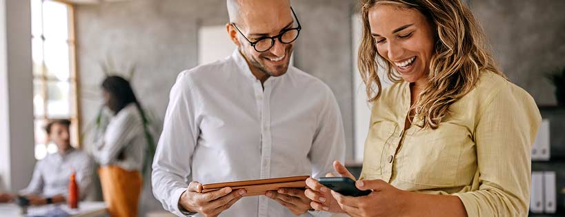 people in office setting looking at mobile and tablet devices
