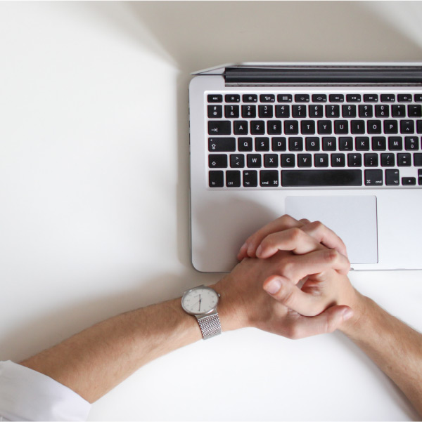 Hands crossed over a laptop.