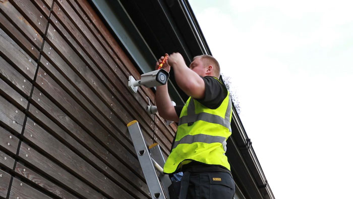 BGE Digital Security worker installing a security camera on a building