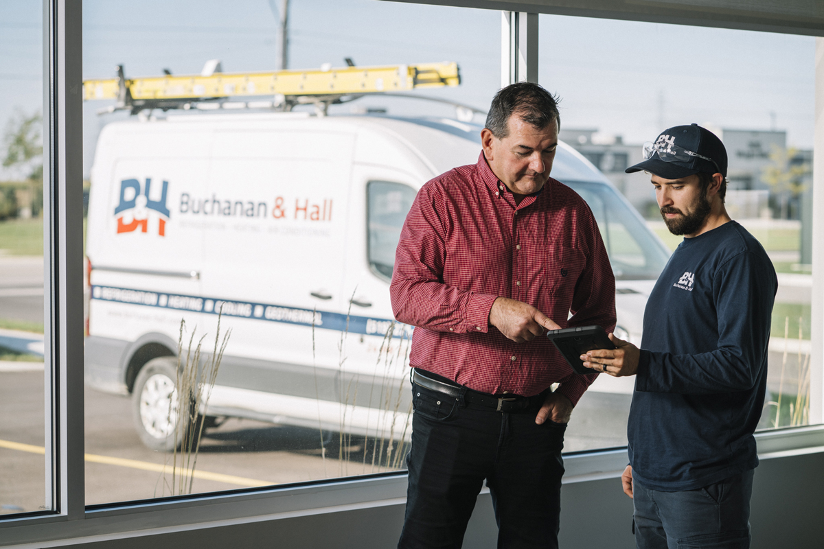 Buchanan & Hall workers in front of a van, looking at an iPad