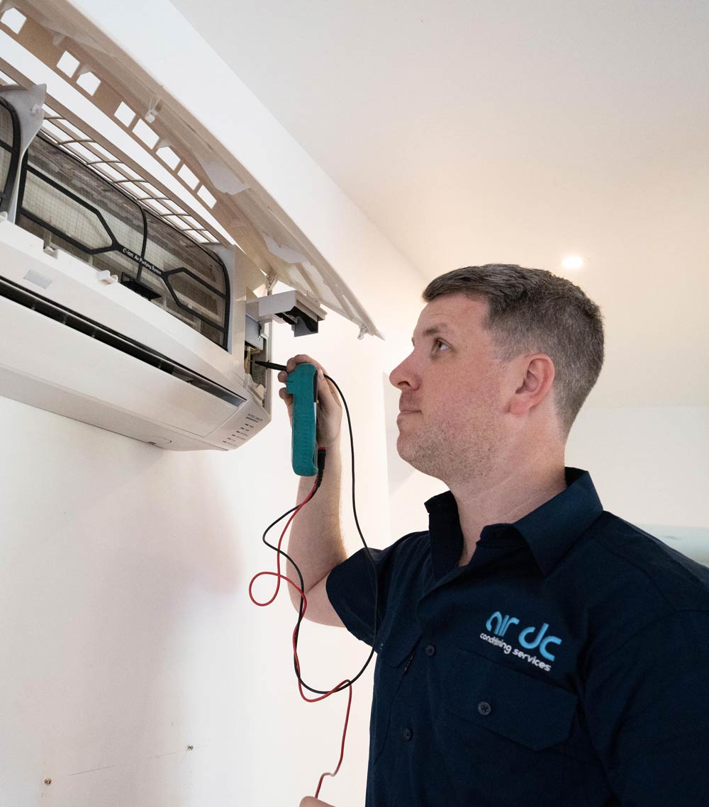 Air DC technician conducting maintenance on an air conditioner