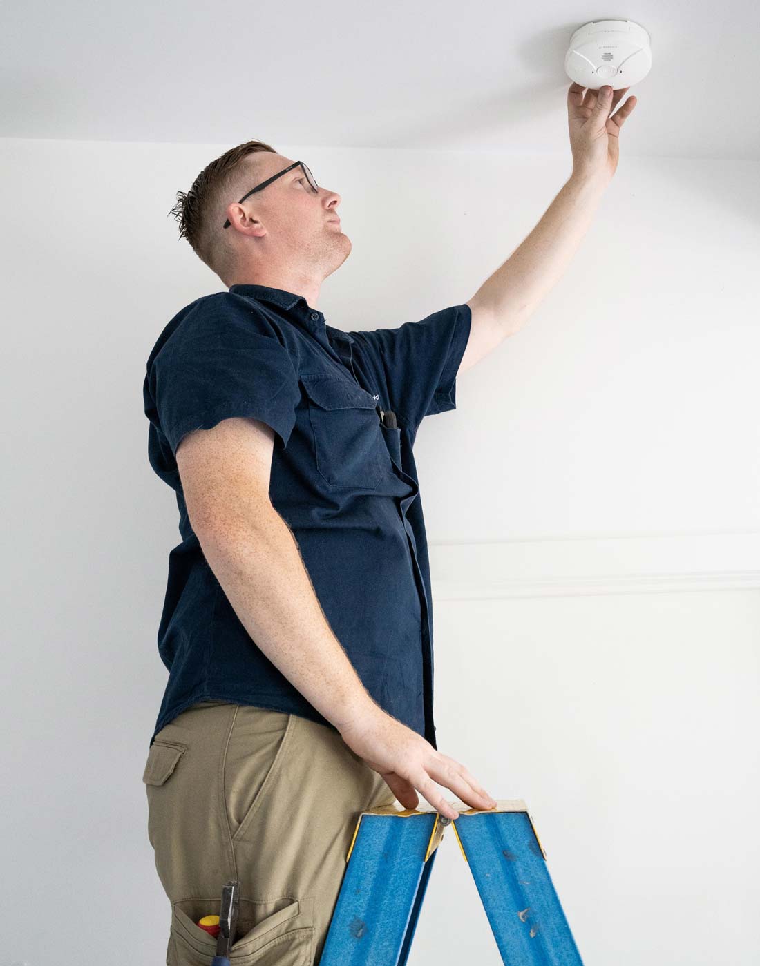 DC Smoke Alarms technician conducting maintenance on a smoke alarm