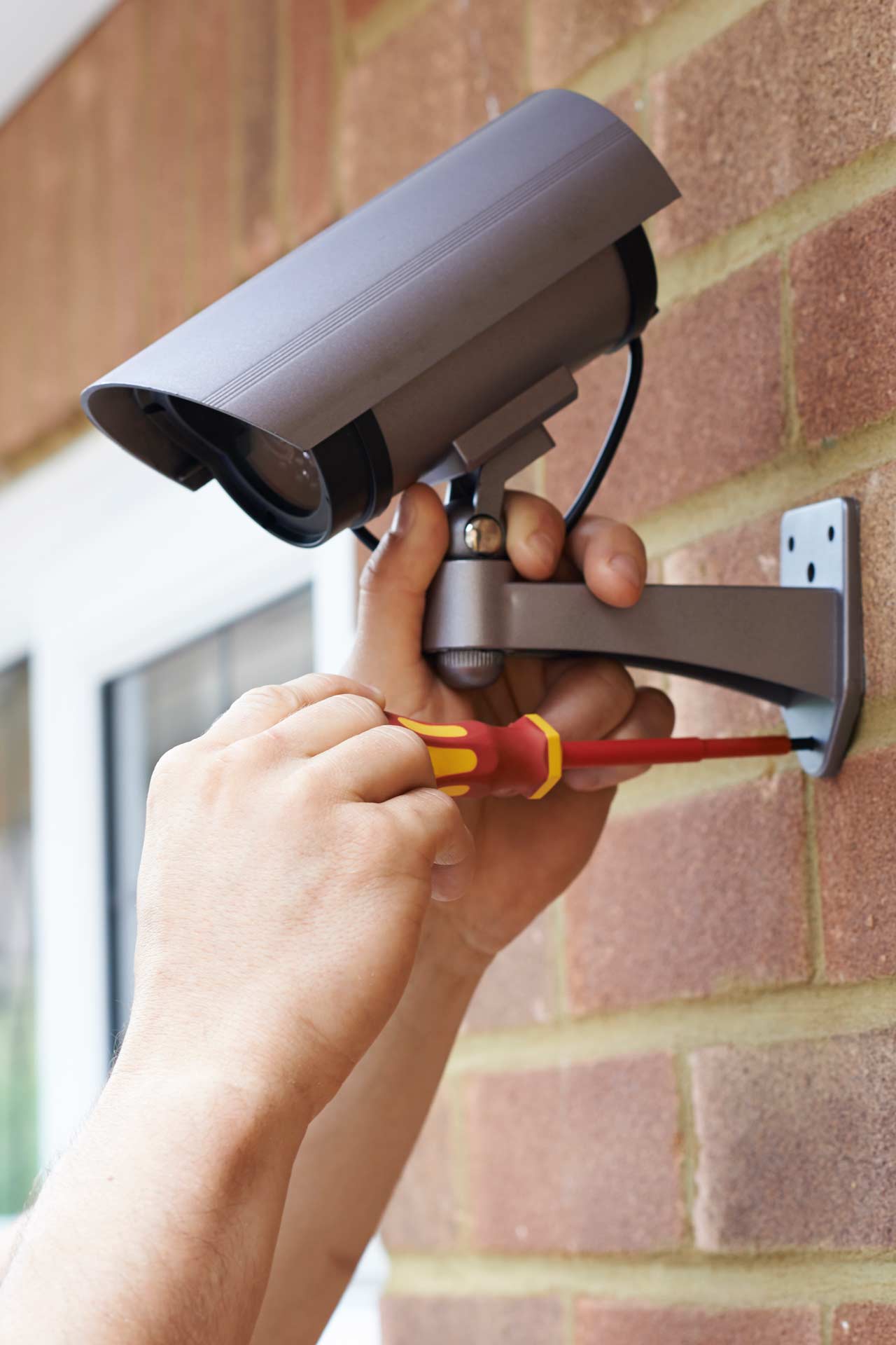 A security business technician installs a security camera outside