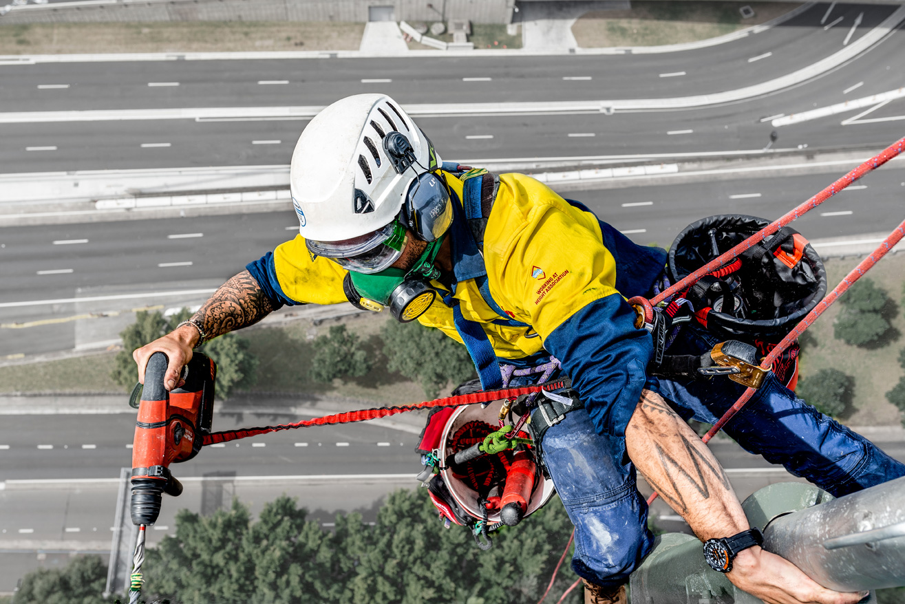 Sky5 worker harnessed to a pole operating a power tool