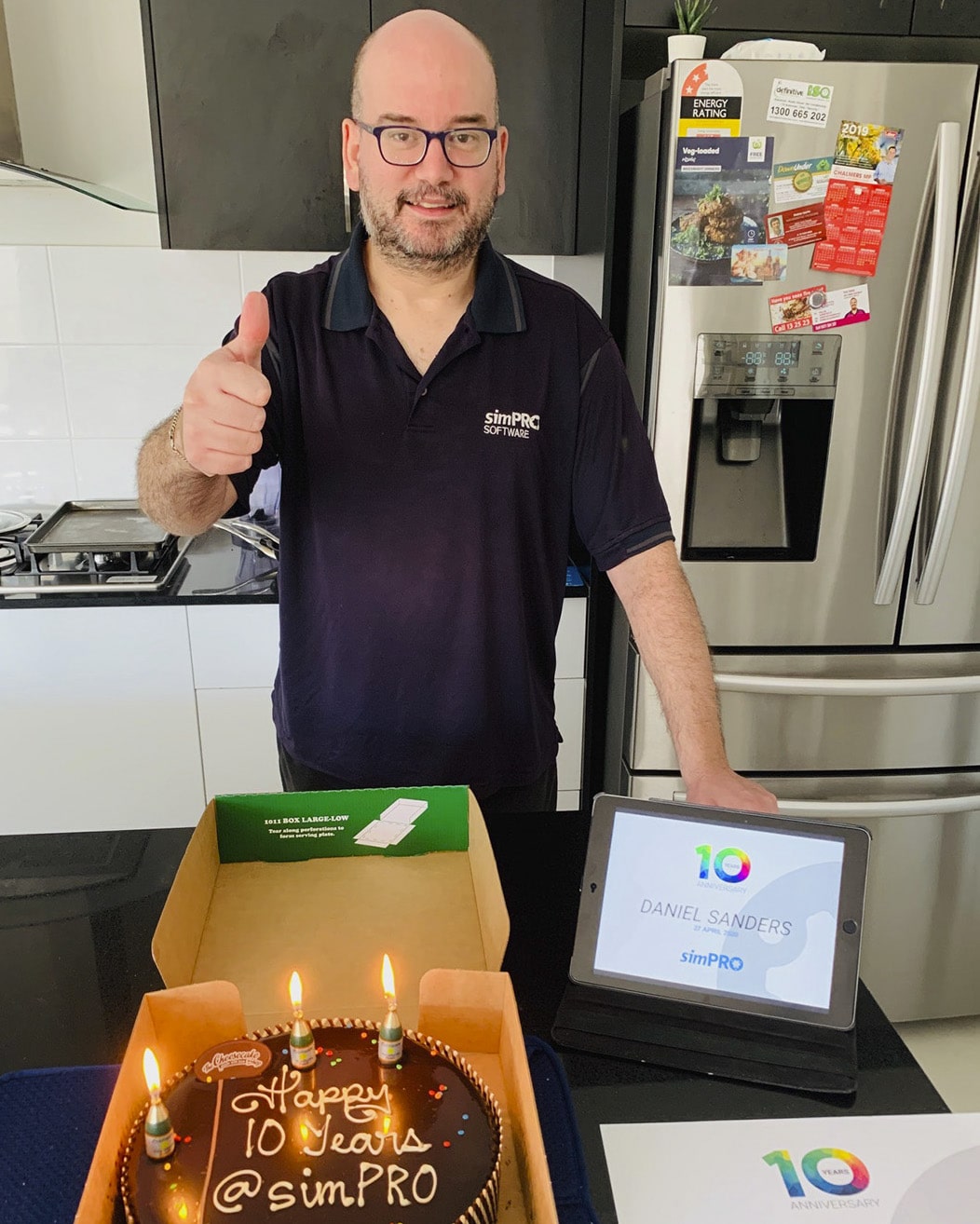 Daniel Sanders posing with his 10 year anniversary certificate and cake.