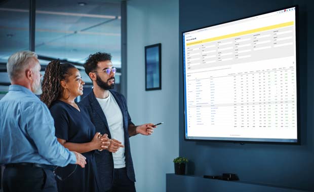 Office workers looking at Simpro dashboard on large screen