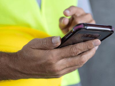 person wearing reflective vest and holding mobile device