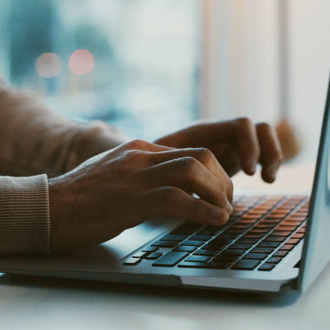 A laptop is open with two hands shown on the keyboard.