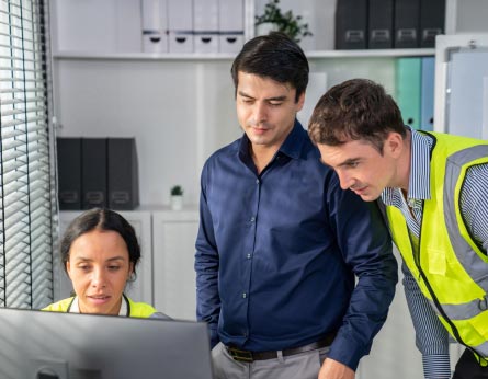 3 workers looking at computer screen in office setting